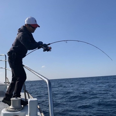 Homem a pescar num barco com roupa preta e boné branco