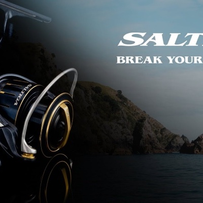 Molinete de pesca preto com detalhes dourados sobre fundo de mar e rochas