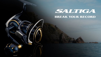 Molinete de pesca preto com detalhes dourados sobre fundo de mar e rochas