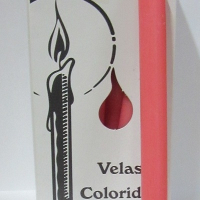 Vela cor-de-rosa cilíndrica junto a caixa branca com desenho e texto
