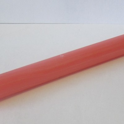 Vela cilíndrica rosa sobre superfície branca