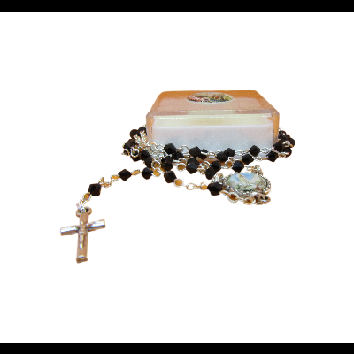 Rosário com contas pretas e correntes douradas sobre caixa branca