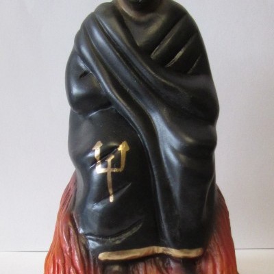 Estátua de homem com manto preto e placa EXÚ CAPA PRETA