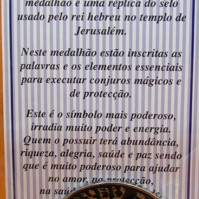 Medalhão dourado Selo de Salomão com inscrições hebraicas na embalagem com texto em português.