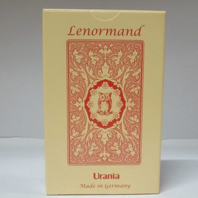 Caixa amarela de baralho Lenormand Urania com ilustração vermelha e texto na caixa