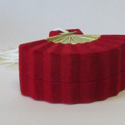 Estojo vermelho em veludo em forma de leque com detalhe dourado e tassel branco.