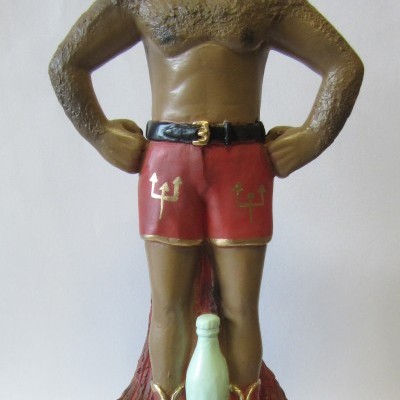 Estátua de homem em calções vermelhos com símbolos dourados em fundo branco