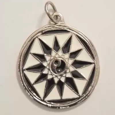 Pingente redondo prateado com padrão geométrico preto e branco e símbolo yin-yang no centro