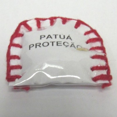 Amuleto de tecido branco com bordado vermelho e etiqueta 'PATUÁ PROTEÇÃO'