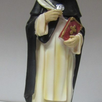 Estátua de S. Tomás Aquino em resina pintada com base redonda e placa descritiva.