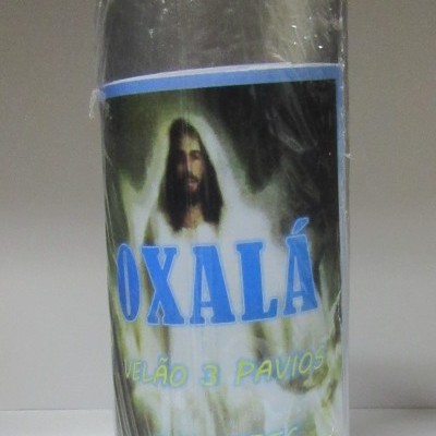 Vela preta com etiqueta azul e verde, imagem de homem e texto Oxalá, velão 3 pavios e 2 cores