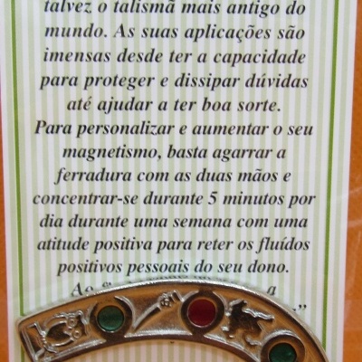 Ferradura da sorte metálica com pedras coloridas embutidas num cartão com texto