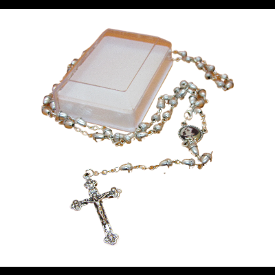 Terço com contas brancas e crucifixo prateado ao lado de caixa plástica
