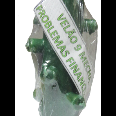 Vela verde de nove mechas em saco plástico com etiqueta escrita 'VELÃO 9 MECHAS PROBLEMAS FINANCI'