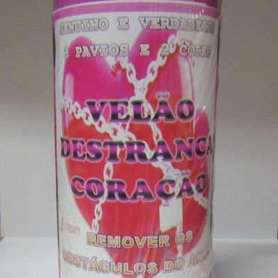 Vela roxa com etiqueta escrita em português sobre amor e obstáculos, decorada com imagem de coração e correntes.