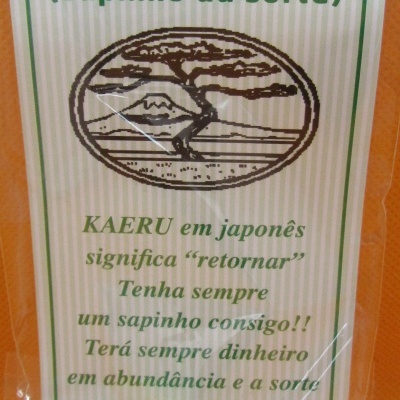 Embalagem cartão com texto verde e sapinho dourado em plástico