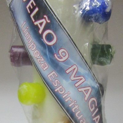 Vela branca decorativa com 9 velas coloridas anexadas e rótulo 'VELÃO 9 MAGIAS Limpeza Espiritual'