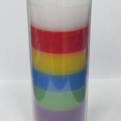 Vela colorida em copo de vidro com várias camadas coloridas.