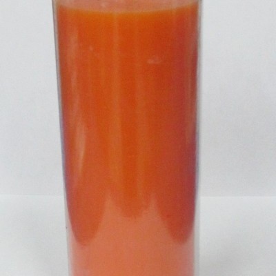 Vela cilíndrica alaranjada em copo transparente sobre fundo branco