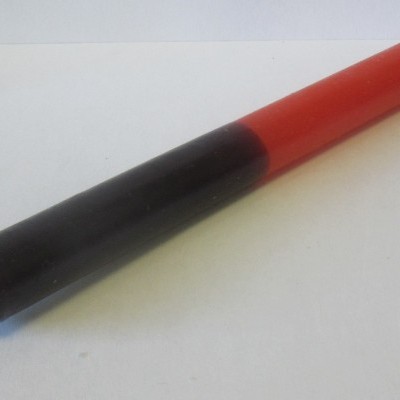 Vela bicolor preta e vermelha com pavio numa extremidade sobre fundo branco