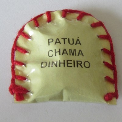 Amuleto amarelo com escrita preta e bordado vermelho sobre fundo branco