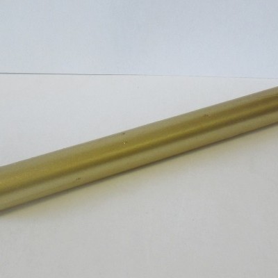 Vela dourada comprida com pavio branco sobre superfície branca