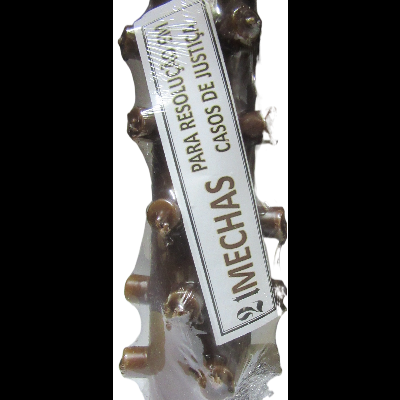 Vela decorativa branca com nós e etiqueta com texto em espanhol.