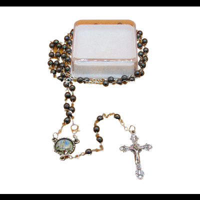 Terço com contas castanhas, medalha colorida e crucifixo prateado sobre caixa transparente
