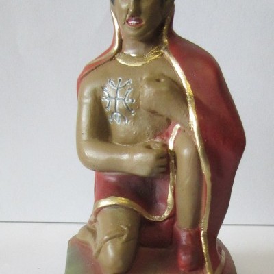 Estátua de homem ajoelhado com coroa e capa vermelha