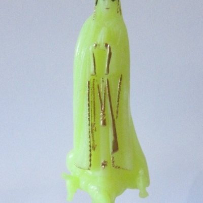 Estátua amarela fluorescente de Nossa Senhora de Fátima com detalhes dourados e base castanha com placa FATIMA