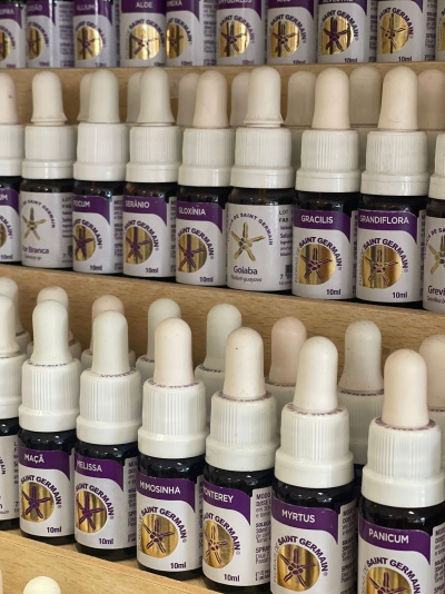 Frascos pequenos de vidro com conta-gotas brancos rotulados Saint Germain em prateleiras de madeira.