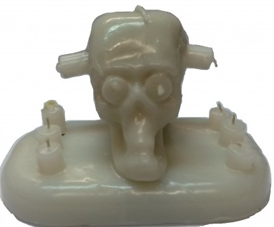 Vela branco com formato de cabeça de monstro e vários pavios