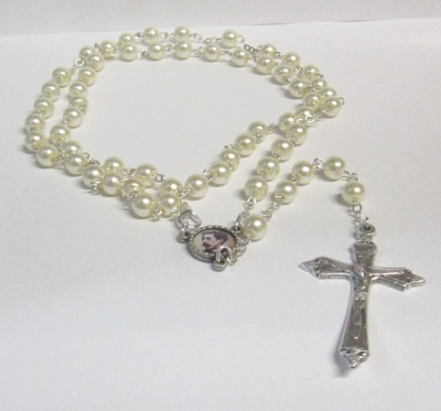 Rosário com pérolas brancas, medalhão com imagem religiosa e cruz prateada detalhada