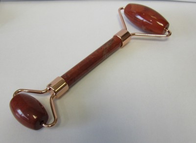 Rolo facial castanho avermelhado com estrutura dourada sobre superfície branca