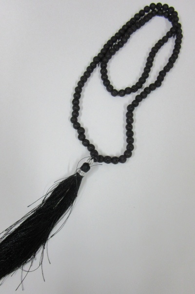 Colar ou rosário com contas pretas e franja preta sobre fundo branco