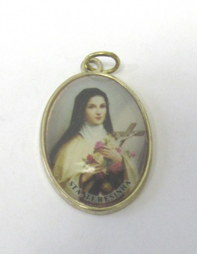 Medalha oval com imagem religiosa de Santa Teresinha, borda dourada