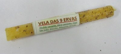 Vela amarela com partículas marrons e etiqueta com texto sobre ervas.