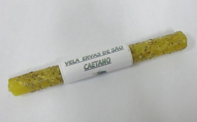 Vela amarela com ervas e rótulo branco com texto