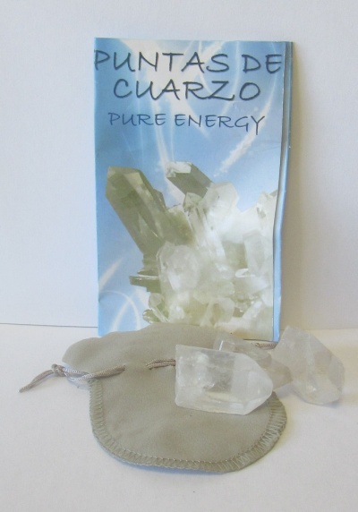 Duas pontas de quartzo transparentes com saco de tecido cinza e cartaz azul com texto PUNTAS DE CUARZO PURE ENERGY