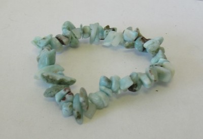 Pulseira de pedras verdes irregulares numa superfície branca.