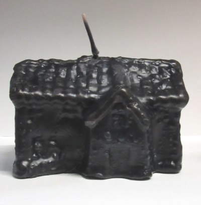 Vela preta em forma de casa com textura de telhado e chaminé