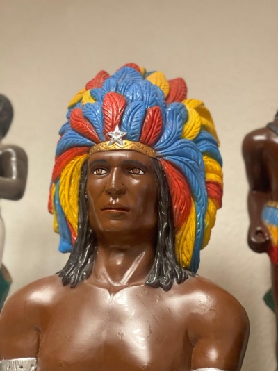 Estátua de homem com cocar colorido de penas