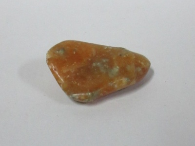 Pedra laranja irregular com manchas brancas sobre fundo branco