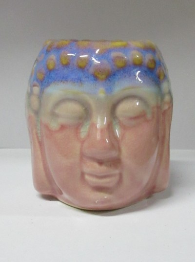 Peça cerâmica esmaltada com forma de cabeça em tons rosa, azul e amarelo
