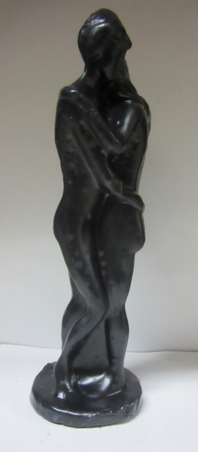 Escultura preta de casal nu a abraçar-se com base circular