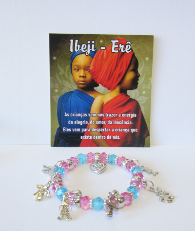Pulseira colorida com pendentes prateados e cartaz com crianças vestidoas de azul e vermelho