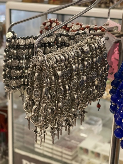 Pulseiras metalizadas prateadas e castanhas com cruzes, em suporte de metal