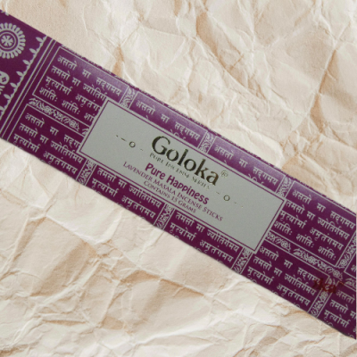 Embalagem de incenso Goloka Pure Happiness de cor roxa e branca sobre papel amassado