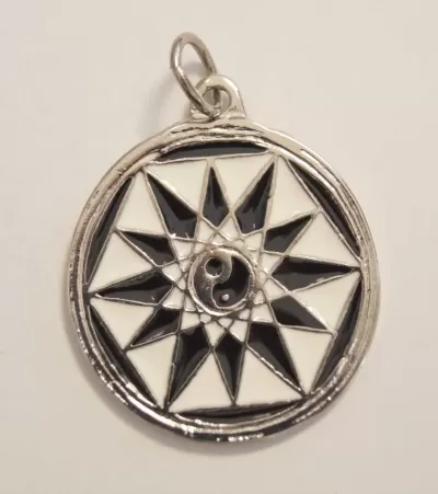 Pingente redondo prateado com padrão geométrico preto e branco e símbolo yin-yang no centro