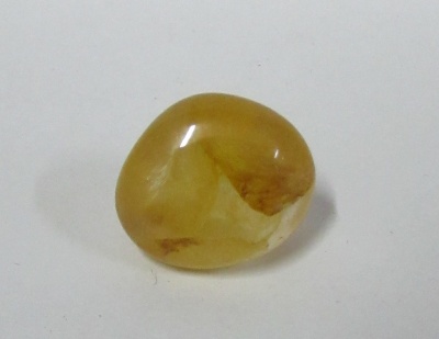 Pedra polida amarela com manchas castanhas sobre fundo branco